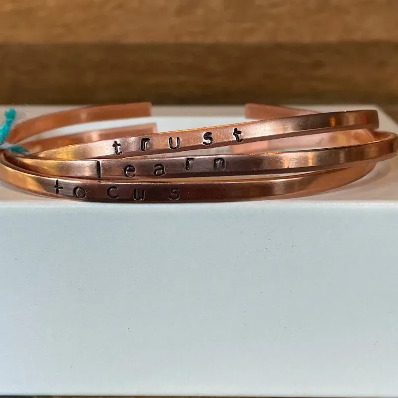 Hand-stamped copper bracelet trio that reads Focus & Learn